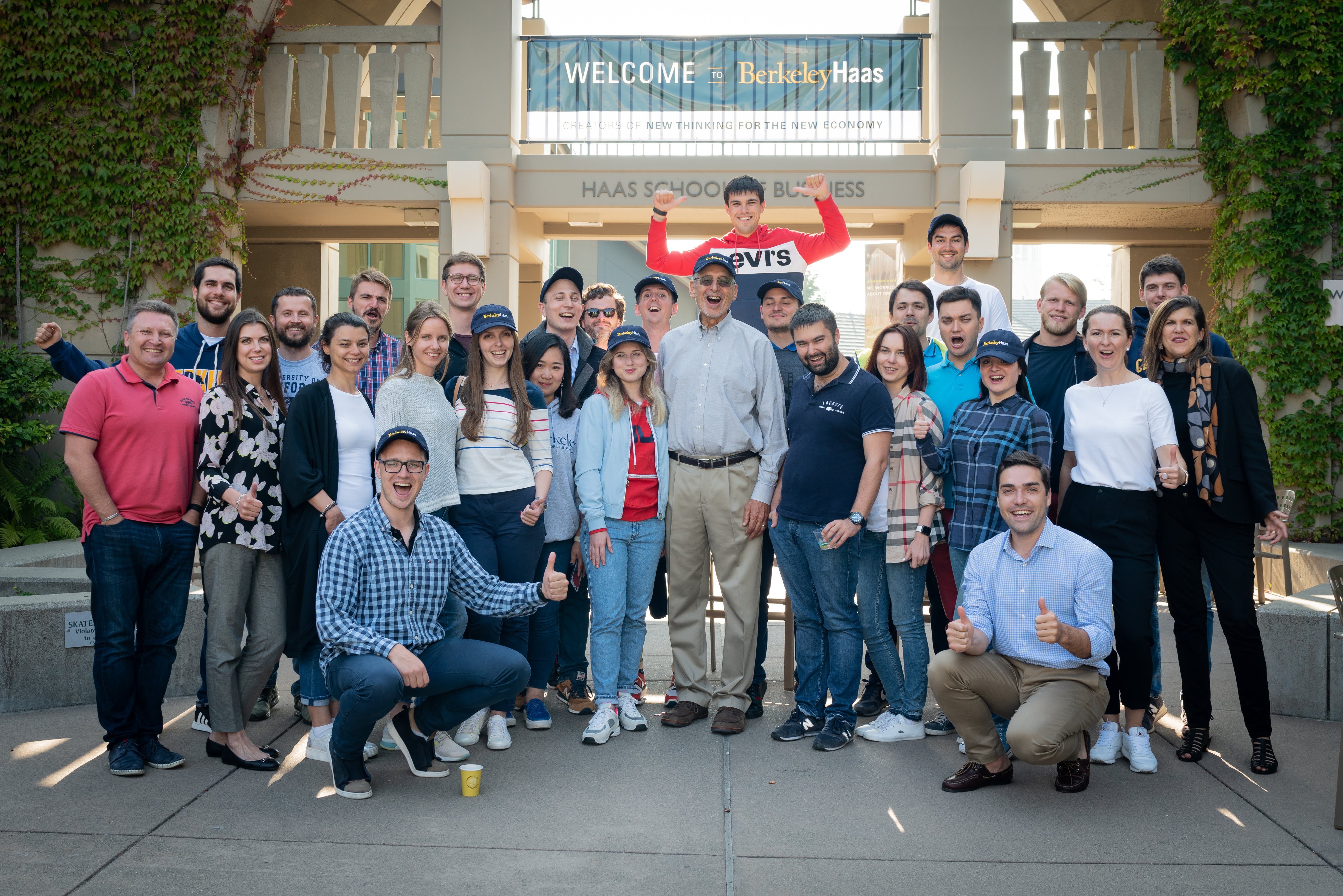Large group posing for a cheerful photo under a Welcome to Berkeley Haas banner.