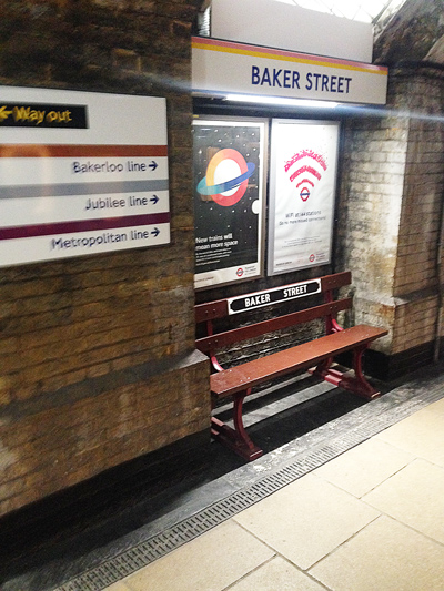 Baker Street Underground platform with Way Out signs for Bakerloo, Jubilee and Metropolitan lines, and a bench