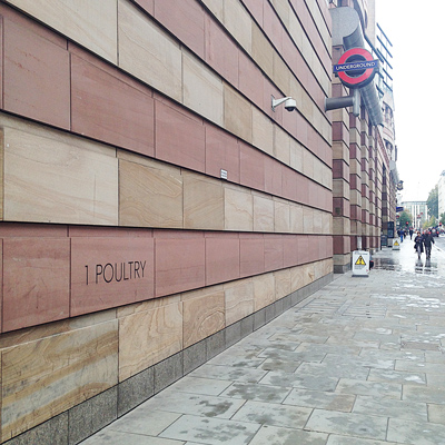 Stone-clad building wall inscribed '1 Poultry' with a London Underground sign on a wet street